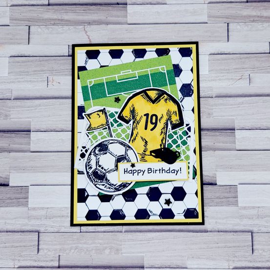 Ein Geburtstagskarte mit Fußball-Thema, mit einem gelben Trikot mit der Nummer 19, einem Fußball und einer Schiedsrichter-Fahne. Die Karte hat einen grünen und weißen Fußballfeld-Hintergrund.