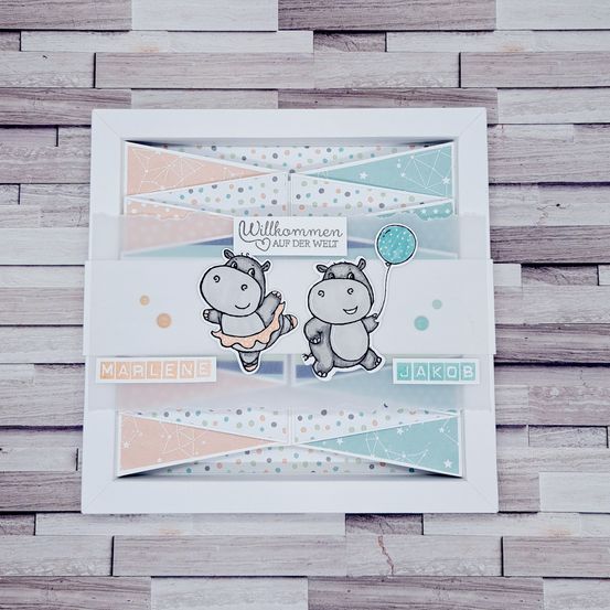 Eine handgefertigte Karte mit zwei Hippos, einer hält einen Ballon, und den Namen Marlene und Jakob. Die Karte liegt auf einem hölzernen Hintergrund.
