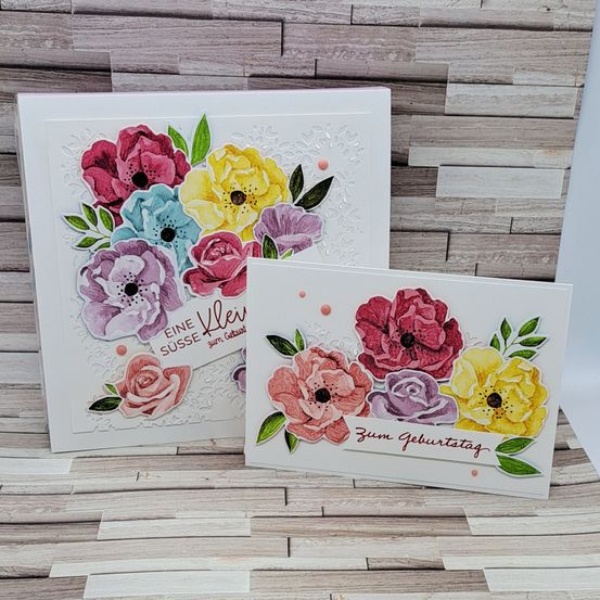 Zwei handgemachte Grußkarten mit Blumendesigns. Die linke Karte hat eine bunte Blumenanordnung mit dem Text 'Eine süße Klein'. Die rechte Karte zeigt ein ähnliches Blumendesign mit dem Text 'Zum Geburtstag'.