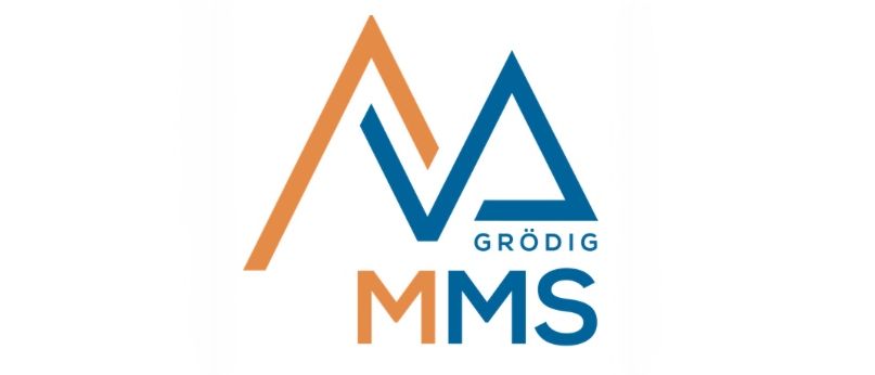Das Grodig MMS Logo zeigt ein blaues und orangefarbenes Dreieck mit einem stilisierten Buchstaben 'M'. Darunter steht der Schriftzug 'Grodig' in Blau, und darunter steht 'MMS' ebenfalls in Blau. Das Logo ist auf weißem Hintergrund.