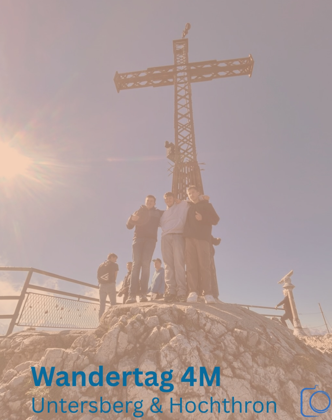 Eine Gruppe von Menschen steht auf einem felsigen Hügel und posiert für ein Foto vor einem großen Kreuz.