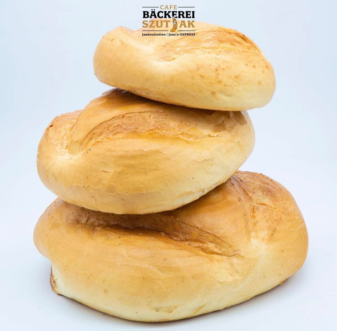 Drei frisch gebackene Brötchen, die übereinander gestapelt sind. Das Bild wurde von oben aufgenommen.