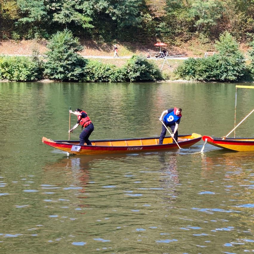 Zwei Personen in einem Kanu auf einem Fluss, jeder hält ein Paddel, mit den Nummern 9 und 8 auf ihren Trikots.