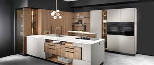 Eine moderne Küche mit einer weißen Insel, Holzschränken und schwarzen Akzenten. Die Küche beinhaltet eine Pendelleuchte, einen Ofen und ein Waschbecken.