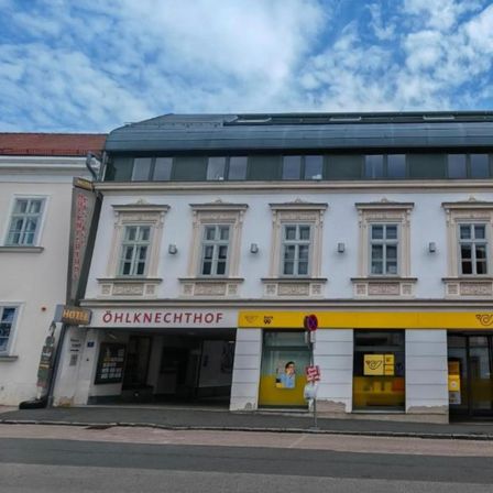 Ein weißes Gebäude mit gelben Akzenten und mehreren Fenstern, das ein Schild mit der Aufschrift Knechthof trägt. Der Eingang ist mit einem gelben Banner gekennzeichnet.