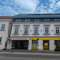 Ein weißes Gebäude mit gelben Akzenten und mehreren Fenstern, das ein Schild mit der Aufschrift Knechthof trägt. Der Eingang ist mit einem gelben Banner gekennzeichnet.