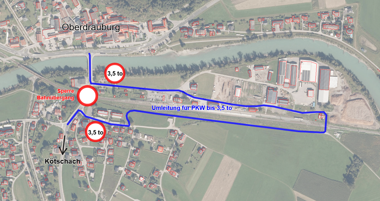 Eine Luftaufnahme zeigt eine Stadt mit beschrifteten Bereichen und einer blauen Linie, die eine Route anzeigt. Die Route beginnt bei 'Sperre Bahnübergang' und endet bei 'Kötschach'. Es gibt mehrere rote Kreise mit Zahlen, die Entfernungen in Kilometern angeben.