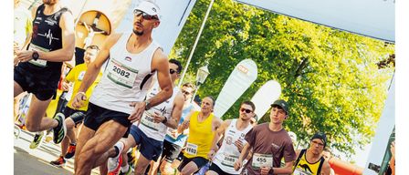 Läufer nehmen an einem Marathon teil und passieren ein Banner für Bad Waltersdorf. Das Banner trägt die Aufschrift 'www.badwaltersdorf.com'. Die Läufer tragen Nummern auf ihren Trikots. Der Slogan lautet 'Radio Steiermark Lauf. Jetzt anmelden.'
