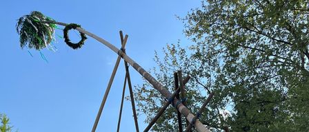 Eine Gruppe von Menschen baut eine große Holzstruktur in einem Park mit Bäumen im Hintergrund.