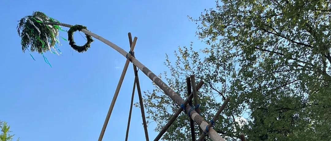 Eine Gruppe von Menschen baut eine große Holzstruktur in einem Park mit Bäumen im Hintergrund.