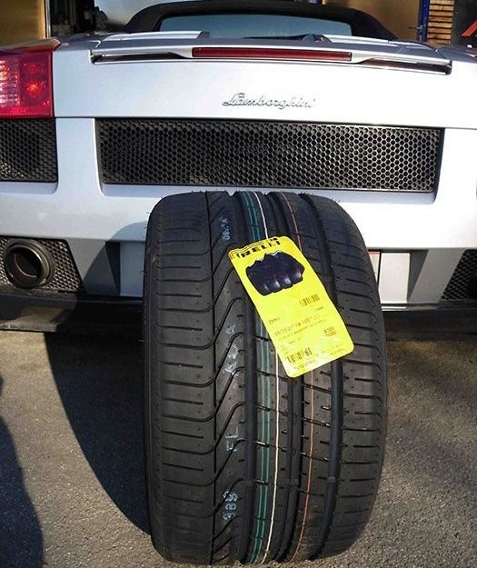 Ein Lamborghini Sportwagen ist geparkt, mit einem Reifen, der ein gelbes Etikett mit Text und Zahlen aufweist. Der Reifen hat mehrere farbige Linien.