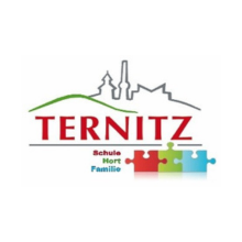 Das Ternitz-Logo zeigt ein Puzzle-Teil-Design mit dem Wort Ternitz in fetten roten Buchstaben über einer Silhouette einer Stadt. Unten steht das Wort 'Schule Hort Familie' in kleineren Buchstaben.