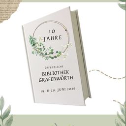 Der Buchdeckel feiert 10 Jahre der Grafenworth öffentlichen Bibliothek, datiert auf den 19. und 20. Juni 2026. Der Einband zeigt einen Kranz aus grünen Blättern und weißen Blumen, mit dem Titel und den Daten in schwarzem Text.