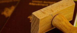 Ein hölzerner Stempel liegt auf einem Reisepass, der auf einem weiteren Reisepass auf einer grünen Oberfläche liegt.