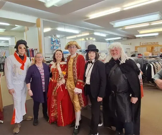 Eine Gruppe von Menschen in verschiedenen Kostümen posiert für ein Foto in einem Raum.