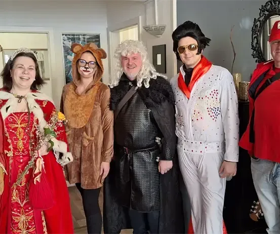 Eine Gruppe von Menschen in verschiedenen Kostümen posiert für ein Foto in einem Raum.