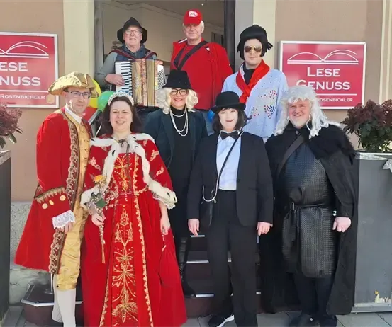 Eine Gruppe von Menschen in Kostümen steht vor einem Gebäude mit roten Schildern.