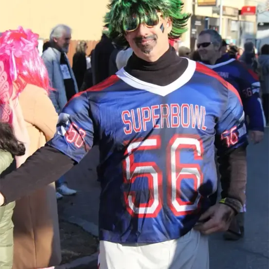 Ein Mann mit grüner Perücke und einem blau-roten Trikot mit der Nummer 66 und dem Text 'SUPERBOWL' steht auf der Straße.