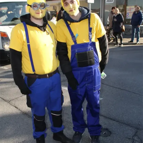 Zwei Männer in gelben und blauen Kostümen stehen auf der Straße, wahrscheinlich für eine Kostümveranstaltung.