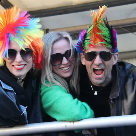 Drei Menschen lächeln für ein Foto. Eine Frau mit bunten Haaren, eine andere mit langen blonden Haaren und ein Mann mit einer schwarzen Lederjacke. Sie tragen Sonnenbrillen.