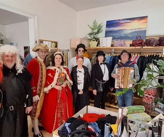 Eine Gruppe von Erwachsenen in Kostümen posiert für ein Foto in einem Bekleidungsgeschäft.