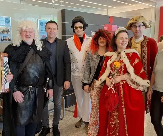 Eine Gruppe von Menschen in verschiedenen Kostümen posiert für ein Foto, darunter ein mittelalterlicher Ritter, eine rothaarige Frau und eine Frau in einem roten Kleid.