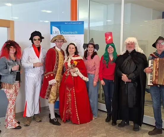 Eine Gruppe von Menschen in Kostümen, die für ein Foto in einem Raum mit einem Schild für LGB Österreich posieren.