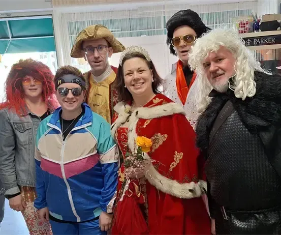 Eine Gruppe von Menschen in Kostümen posiert für ein Foto in einem Geschäft. Eine Person spielt Akkordeon.