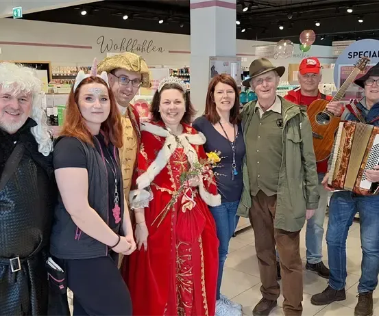Eine Gruppe von Menschen in Kostümen posiert für ein Foto in einem Geschäft mit einem Schild, das 'Special' steht, und Regalen mit Produkten im Hintergrund.