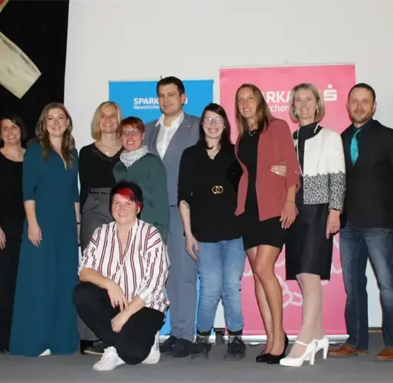 Eine Gruppe von Menschen posiert für ein Foto vor einem Hintergrund mit verschiedenen Logos.