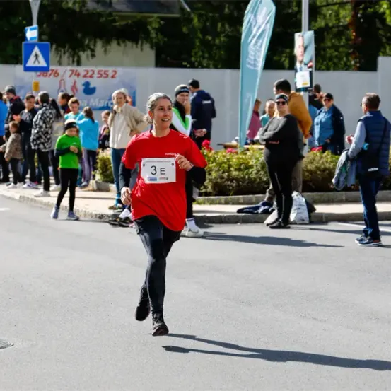 Ein Marathonläufer mit der Nummer 3E auf dem Trikot läuft auf der Straße, während eine Menschenmenge zuschaut.