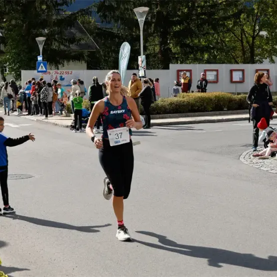 Eine Frau mit der Nummer 37 läuft einen Marathon, während viele Menschen am Straßenrand zusehen.