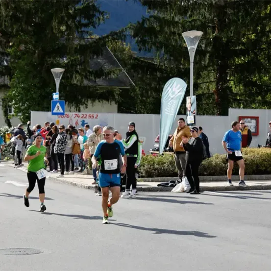 Läufer nehmen an einem Marathon in einem städtischen Umfeld teil, umgeben von Zuschauern und Grünflächen.