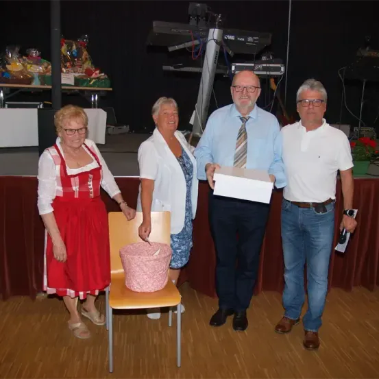 Vier Menschen stehen lächelnd in einem Studio. Zwei Männer und zwei Frauen. Ein Mann hält eine Box und ein Blatt Papier.