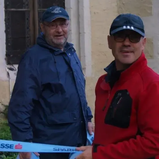 Zwei Männer in Jacken halten ein Band mit dem Wort Spark in der Hand und stehen nebeneinander draußen.