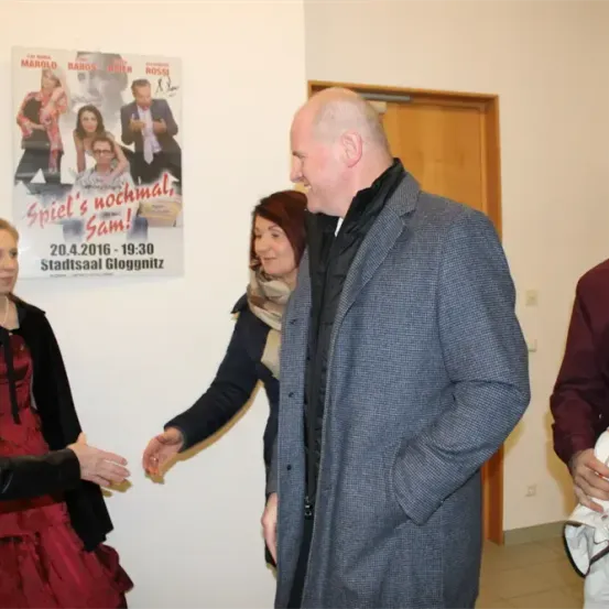 Eine Gruppe von Menschen steht an einer Wand mit einem Plakat, das ein Ereignis im Stadtsaal Gloggnütz am 20. April 2016 bewirbt.