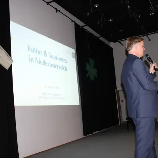 Ein Mann spricht in ein Mikrofon vor einer Projektionsleinwand, die 'Kultur & Tourismus in Niederosterreich' anzeigt. Das Präsentationsdatum ist 5. Juni 2013.