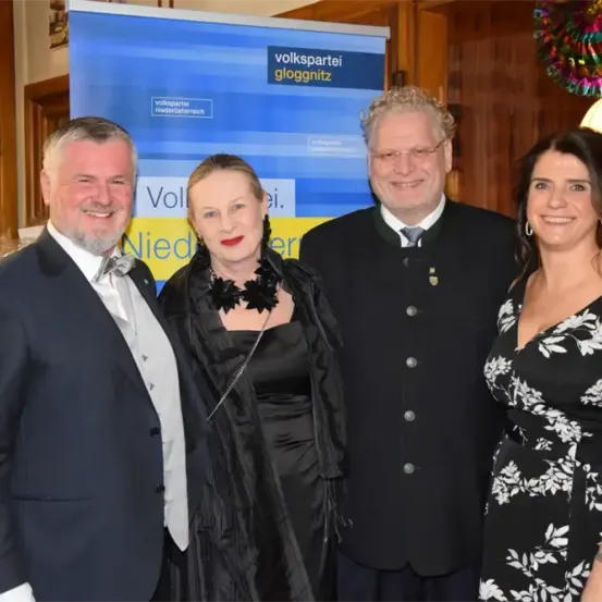 Vier Menschen stehen in formeller Kleidung nebeneinander, lächeln für ein Foto vor einem Volkspartei-Banner.