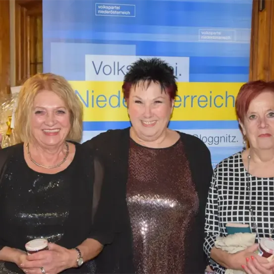 Drei Frauen stehen vor einem 'Volkspartei Niederosterreich'-Banner. Sie halten Tassen und sehen fröhlich aus.