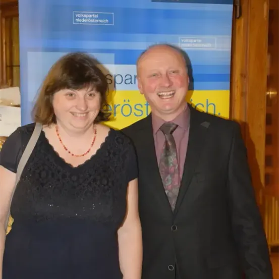 Ein Mann und eine Frau stehen eng beieinander und lächeln für ein Foto vor einem Banner mit 'Volkspartei Niederösterreich'.