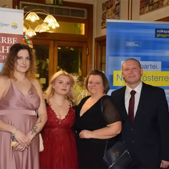 Vier Personen, zwei Frauen und zwei Männer, stehen gemeinsam für ein Foto. Die Frauen tragen Kleider und die Männer sind in Anzügen. Hinter ihnen befindet sich ein Banner mit der Aufschrift 'Niederösterreich'.