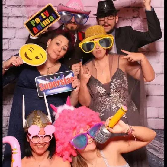 Eine Gruppe von Menschen in Kostümen posiert mit Requisiten in einem Fotokabinen für ein Foto.