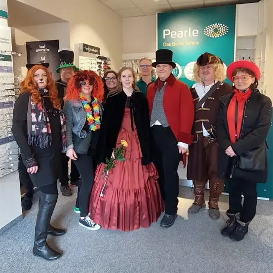 Eine Gruppe von Menschen in verschiedenen Kostümen posiert für ein Foto vor einem Pearl-Schild.