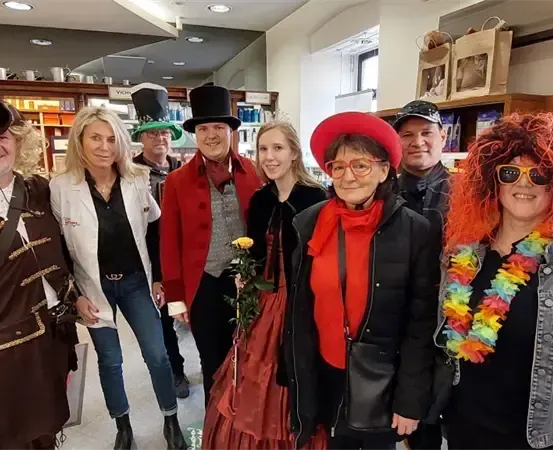 Eine Gruppe von Menschen in Kostümen und Hüten posiert für ein Foto in einem Geschäft mit Regalen voller Artikel.