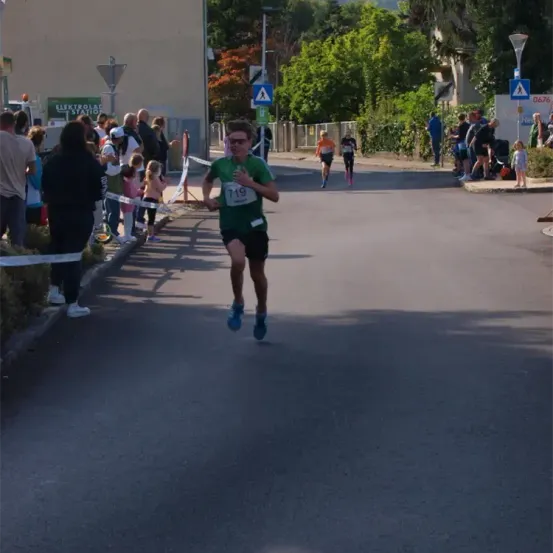 Ein Marathonläufer mit der Nummer 719 auf dem Shirt läuft auf einer Straße, an der mehrere Zuschauer stehen.