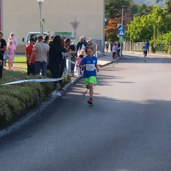 Ein Läufer mit der Nummer 746 sprintet die Straße hinunter, während eine Menge vom Bürgersteig aus zusieht.