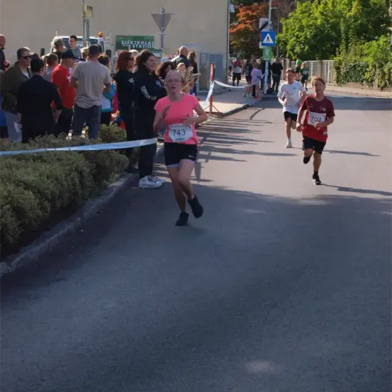 Läufer nehmen an einem Marathon teil, mit mehreren Zuschauern an der Seite, eine Person mit der Nummer 743 ist in Führung.