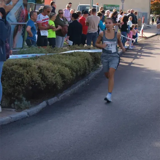 Ein Marathonläufer mit einem grauen Shirt und grauen Shorts mit der Nummer 721 läuft die Straße entlang, während viele Menschen zusehen.