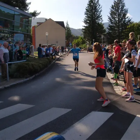 Läufer bei einem Marathonrennen, ein Läufer überquert die Ziellinie, mit Zuschauern auf beiden Straßenseiten.