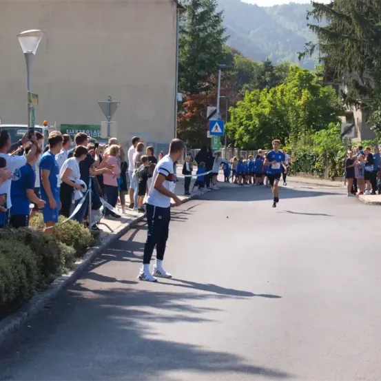 Ein Mann läuft einen Marathon auf einer Stadtstraße, während Zuschauer ihn anfeuern.